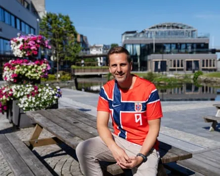 Andreas Vollusund, mayor of Bryne, sits on a table in the town wearing a red Haaland shirt